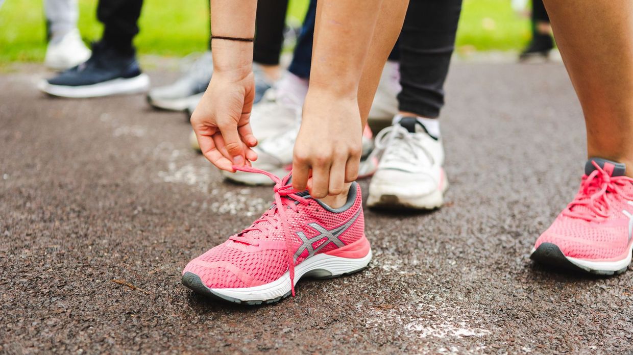 Jemand bindet sich seine Schuhe beim Parklauf.