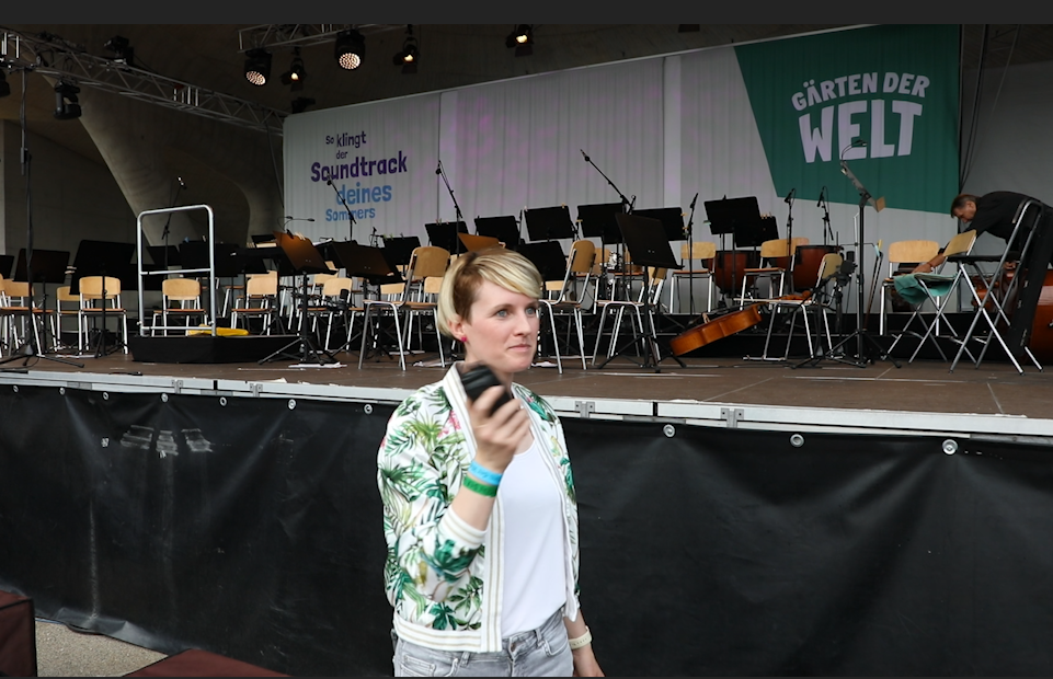 Ute Hessenberger, Projektleiterin im Veranstaltungsmanagement bei Grün Berlin, steht vor der Arena in den Gärten der Welt und hält ein Walkie Talkie in der Hand