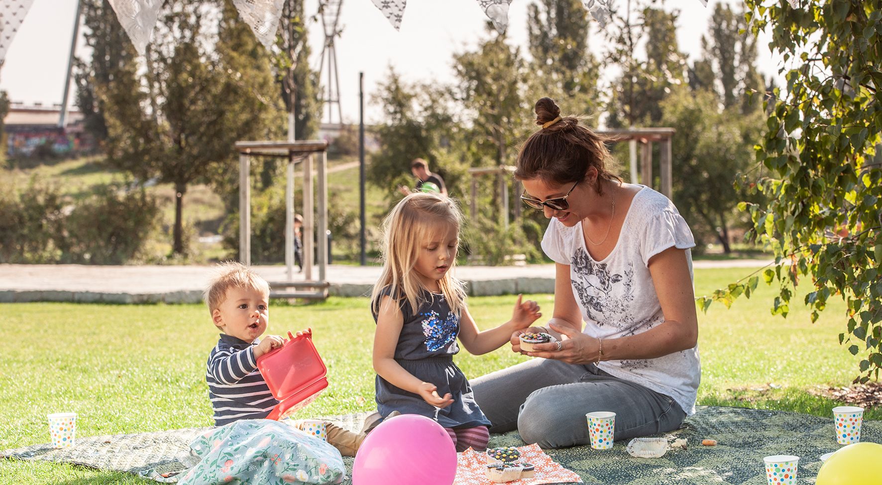 Das Bild zeigt eine Frau mit zwei Kindern beim Picknick.
