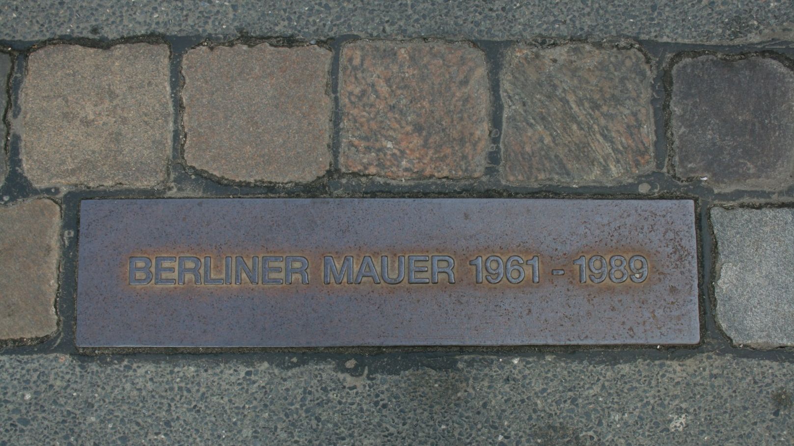 Eine in den Boden eingelassene Tafel zeigt den ehemaligen Standort der Berliner Mauer an.