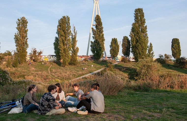 Das Bild zeigt eine Gruppe Jugendlicher auf der Wiese vor dem Hügel im Mauerpark.