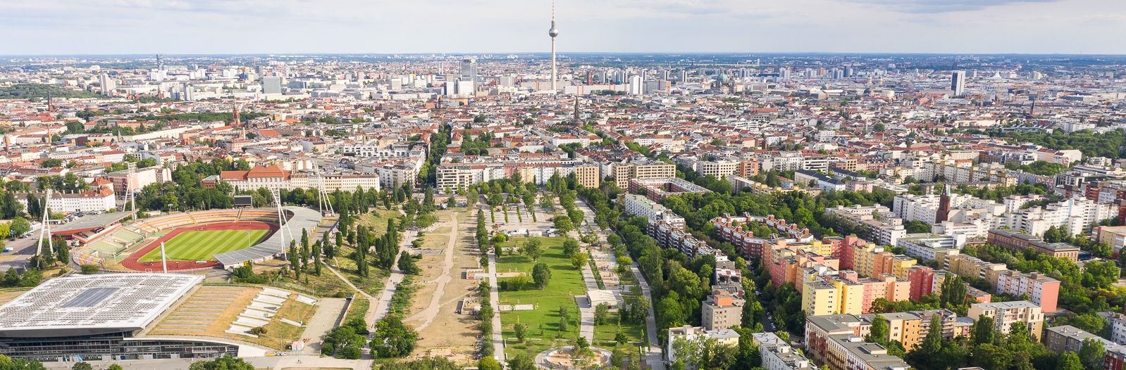 Zu sehen ist der Berliner Mauerpark mit der Bestandsfläche und den neuen Erweiterungsflächen aus der Luft, im Hintergrund die Stadt Berlin mit dem Fernsehturm