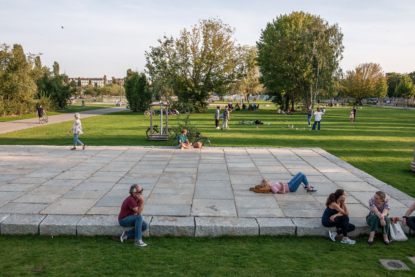 Das Bild zeigt Menschen im Mauerpark, sie liegen oder sitzen, allein oder zusammen auf der Wiese.