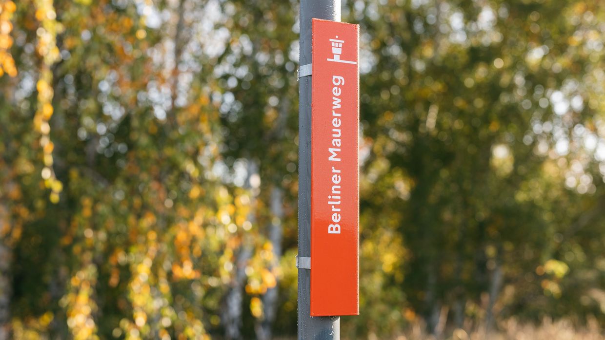 Ein roter Wegweiser des Berliner Mauerwegs.