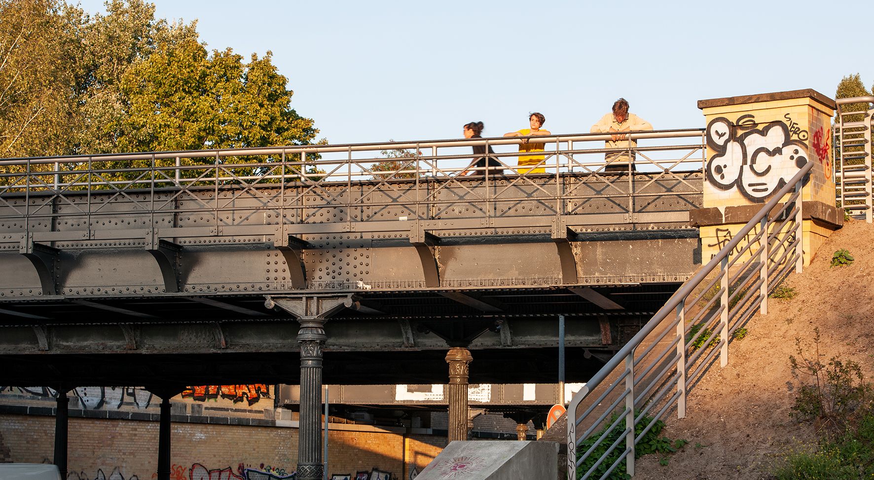Der Blick hoch auf die Yorckbrücken, Menschen lehnen am Geländer.